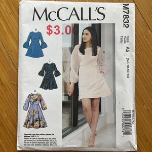 Op de afbeelding: McCall's naaipatroon M7832 voor een damesjurk. Het patroon bevat verschillende jurkstijlen met verschillende mouw- en rokontwerpen. De maat is A5 (6-8-10-12-14). De omslag toont een vrouw in een lichtroze jurk.