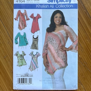 Peut inclure: Patron de couture Simplicity numéro 4164, collection Khaliah Ali, taille FF 18W-24W, EUR 44-50 FR 46-52. Le patron comprend des instructions pour réaliser une variété de hauts avec différentes encolures, manches et embellissements. Le patron est imprimé sur un fond blanc avec un motif floral rose et blanc.