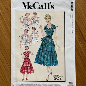 Puede incluir: Patrón de costura vintage McCall's M8280 para las tallas 6-8-10-12-14. El patrón presenta un vestido con un escote de corazón y un lazo en la cintura. El vestido se muestra en un estampado floral verde y blanco y un estampado de cuadros rojos y blancos.