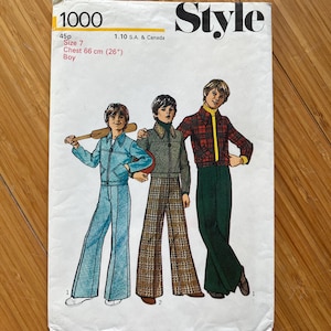 May include: Vintage sewing pattern for boys' trousers. The pattern is for size 7, with a chest measurement of 66 cm. The pattern includes three different styles of trousers, one with a plaid pattern, one with a solid green colour, and one with a blue denim look. The pattern is labelled "Style 1000" and is for sale for 45 pence.