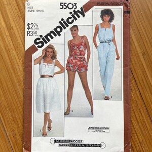 Peut inclure: Patron de couture Simplicity numéro 5503 pour une combinaison, un short et une robe. Le patron est pour les tailles de jeunes femmes et comprend des instructions pour la confection des vêtements. Le patron est imprimé sur du papier brun avec un fond blanc.