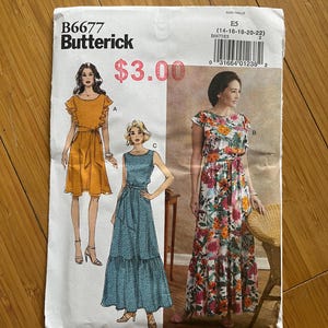 Peut inclure: Un patron de couture Butterick, B6677, avec des illustrations de trois modèles de robes. Le patron comprend les tailles E5 (14-16-18-20-22). Les robes comprennent une robe courte orange, une longue robe bleue et une robe à imprimé floral.