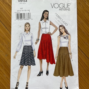 Puede incluir: Patrón de costura Vogue Patterns V9154 para las tallas 6-8-10-12-14. El patrón incluye tres estilos de falda diferentes: una falda a cuadros con una blusa blanca, una falda roja de línea A con una blusa blanca y una falda marrón de línea A con una camiseta blanca.