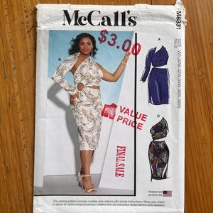 May include: McCall's sewing pattern M8331. The pattern features a woman in a floral print dress with cutouts. The cover includes illustrations of different dress styles. Text includes "Final Sale" and "Value Price".