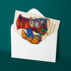 Puede incluir: Un sobre blanco que contiene una tarjeta de Navidad. La tarjeta presenta dos ratones, uno gris y otro marr&oacute;n, con regalos y un buz&oacute;n rojo. La tarjeta dice "Christmas New Year".