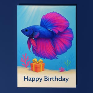 May include: A birthday card with a blue and pink betta fish illustration, a gift box, and the text "Happy Birthday." The fish has blue scales and pink fins. The gift box is orange with a yellow bow. The background depicts an underwater scene in light blue.