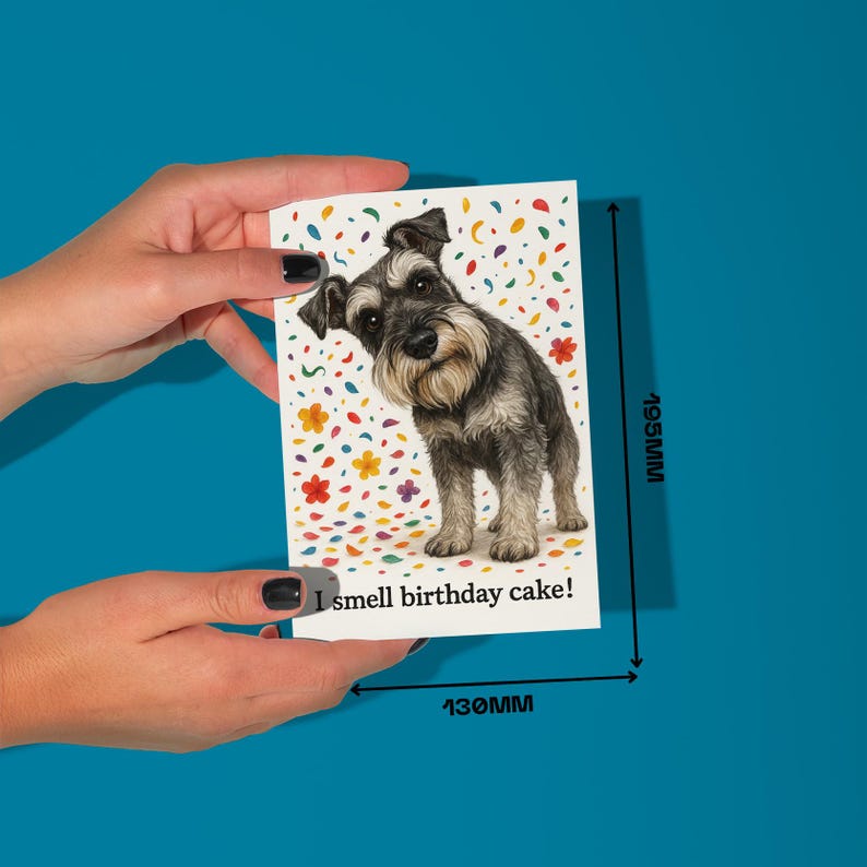 May include: A birthday card featuring a Schnauzer dog illustration with colorful confetti and floral accents. The card measures 195mm x 130mm and has the text "I smell birthday cake!" on the bottom.
