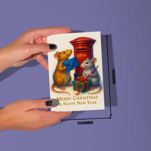 Puede incluir: Tarjeta de Navidad con una ilustraci&oacute;n de dos ratones, un buz&oacute;n rojo y un regalo. La tarjeta dice "Merry Christmas & Happy New Year". La tarjeta mide 19,5 cm de alto y 13 cm de ancho.