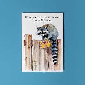 Handgemaakte schattige wasbeer die een klein cadeautje afgeeft! Fijne verjaardag! Kaart Grappige dieren Kaart Premium wenskaart en envelop