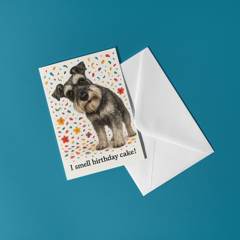 May include: A birthday greeting card featuring a Schnauzer dog with the text "I smell birthday cake!" The card has a colorful confetti background and is accompanied by a white envelope. The background is a solid teal color.
