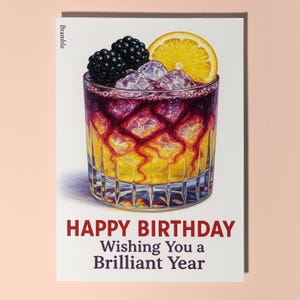 Puede incluir: Tarjeta de felicitación de cumpleaños con una ilustración en acuarela de un cóctel con moras y una rodaja de limón. El vaso contiene hielo y una bebida en capas. El texto dice "HAPPY BIRTHDAY Wishing You a Brilliant Year."