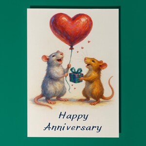 May include: A charming anniversary card featuring two mice. One mouse holds a red heart balloon, the other a gift. The card has the words "Happy Anniversary" in blue script. The image is set against a white background.
