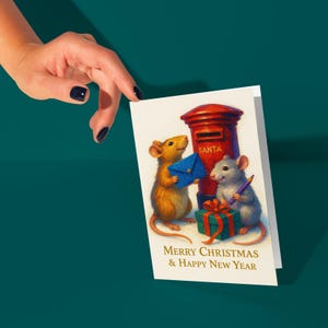 Puede incluir: Una tarjeta de Navidad con dos ratones, un buz&oacute;n rojo y un regalo envuelto. Un rat&oacute;n sostiene un sobre azul, el otro un bol&iacute;grafo morado. La tarjeta dice "MERRY CHRISTMAS & HAPPY NEW YEAR."