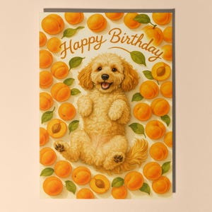 May include: A greeting card featuring a happy, light brown dog lying on its back, surrounded by apricots and green leaves. The words "Happy Birthday" are written in a flowing script above the dog.