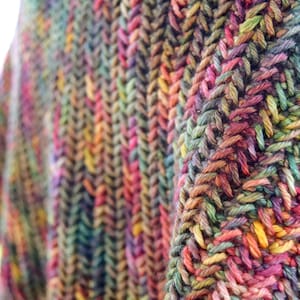 Puede incluir: Primer plano de una tela de crochet multicolor con un patr&oacute;n de punto de espiga. La tela est&aacute; hecha con una variedad de tonos de hilo marr&oacute;n, verde, rojo, naranja y amarillo.