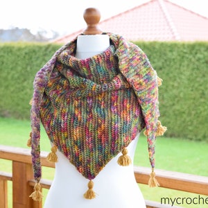Puede incluir: Un chal de ganchillo colorido con forma triangular y borlas. El chal est&aacute; hecho con una variedad de colores, incluyendo verde, azul, rojo y amarillo.
