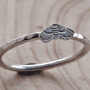 May include: A silver ring with a hammered band and a small, detailed owl design.