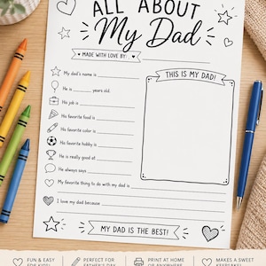May include: A white Father's Day activity sheet with fill-in-the-blank prompts. The sheet says "ALL ABOUT My Dad" and includes spaces to write about Dad's name, job, and favourite things. Crayons and a pen are on the table.
