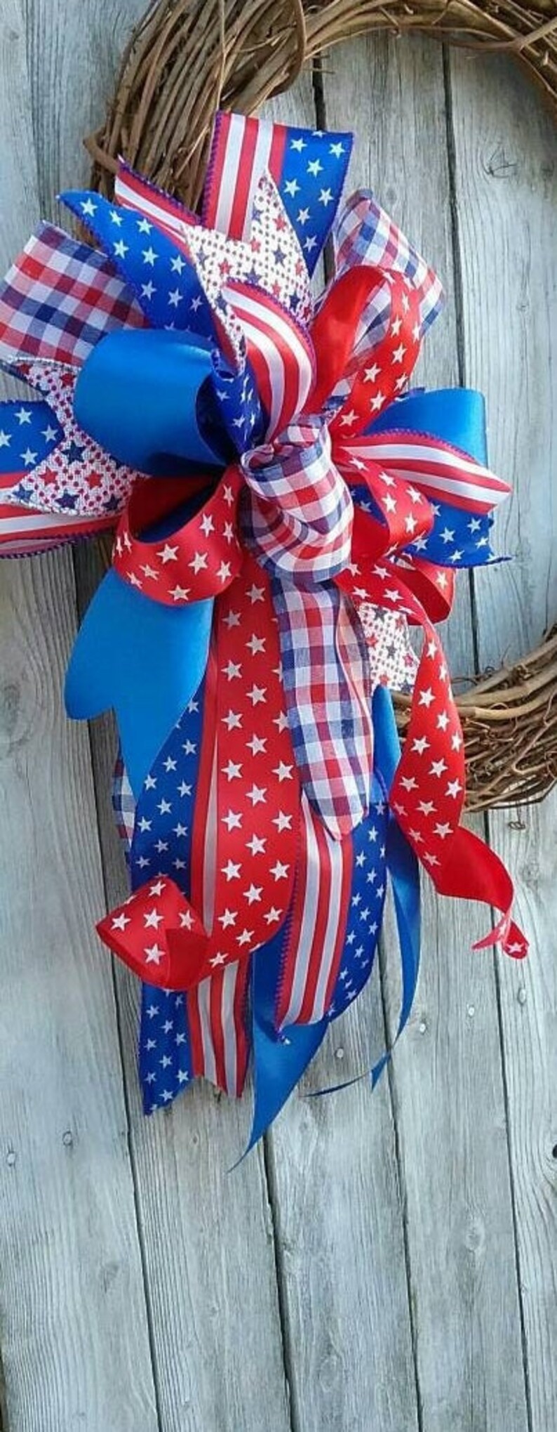 May include: A red, white, and blue patriotic bow with stars and stripes, gingham, and solid blue ribbon. The bow is tied around a wreath.