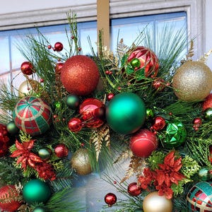 May include: A Christmas wreath with green pine branches, red and gold ornaments, and red poinsettia flowers.