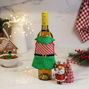 May include: A white ceramic mug with a black handle and the text "But First, Coffee" in a bold, black font. The mug is filled with a dark liquid, likely coffee, and sits on a light-colored surface.