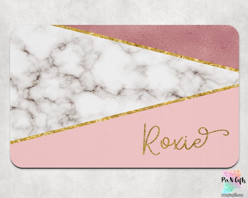 Op de afbeelding: Een roze en wit marmerontwerp met gouden accenten en de naam "Roxie" in gouden schrift.