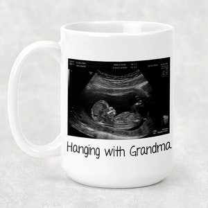 Może przedstawiać: Biały kubek ceramiczny z czarno-białym obrazem USG dziecka i tekstem "Hanging with Grandma".