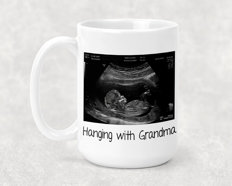 Może przedstawiać: Biały kubek ceramiczny z czarno-białym obrazem USG dziecka i tekstem "Hanging with Grandma".