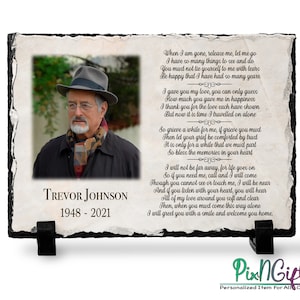 May include: A black slate plaque with a photo of a man wearing a hat and scarf. The plaque has the text "Trevor Johnson 1948-2021" and a poem about remembering a loved one.