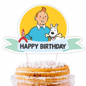Könnte beinhalten: Ein Tortenaufsatz mit einer Cartoon-Illustration eines Jungen und eines Hundes mit einem Knochen, vor einem gelben Kreis. Das Banner lautet "HAPPY BIRTHDAY". Der Kuchen ist ein mehrschichtiger Biskuitkuchen mit Marshmallow-Belag.