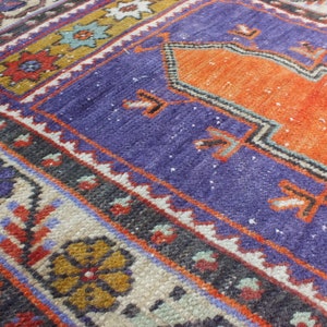 May include: A close-up of a colorful woven rug with intricate patterns in shades of orange, blue, red, and white. The rug has a traditional design with a central medallion and borders.