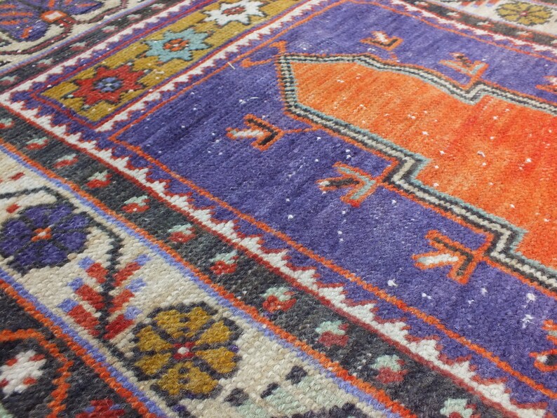 May include: A close-up of a colorful woven rug with intricate patterns in shades of orange, blue, red, and white. The rug has a traditional design with a central medallion and borders.