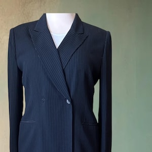 May include: A black pinstripe suit with a double-breasted jacket and matching pants.