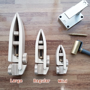 May include: Three wooden leather working tools in different sizes, labelled "Large", "Regular", and "Mini". A silver metal tool and a brass mallet are also shown.