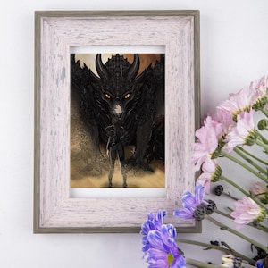 Peut inclure: Impression d'art encadrée représentant une illustration fantastique d'une personne devant un grand dragon noir. Le dragon a des yeux orange vif. Le cadre est blanc vieilli. Des fleurs roses et violettes ornent le premier plan.