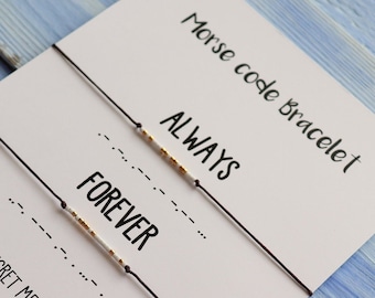 May include: Two black string bracelets with white and gold beads spelling out the words "ALWAYS" and "FOREVER" in Morse code. The bracelets are displayed on a white card with the text "Morse code bracelet" and "SECRET MESSAGE".