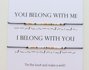 Puede incluir: Dos pulseras de cuerda negra con cuentas blancas y doradas. Las pulseras deletrean "You belong with me" y "I belong with you" en código Morse.