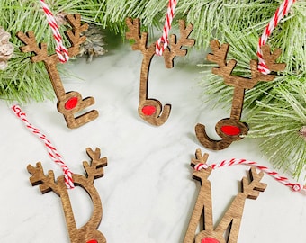 May include: Six wooden reindeer ornaments with red noses and antlers. Each ornament is attached to a red and white twine string.