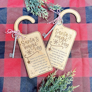 May include: A wooden door hanger with a key attached. The hanger is decorated with a snowflake and the text "Santa's magic key". The text reads: "There is no chimney as you can see. So here's a special magic key. Please use this key on Christmas Eve and put it back before you leave!"