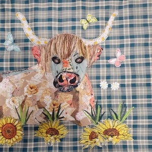 May include: A colourful patchwork fabric Highland cow against a brown, white and blue plaid background. The cow is decorated with fabric flowers, butterflies and daisies.