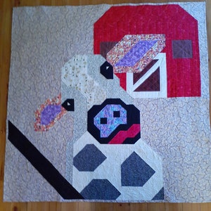 May include: A patchwork quilt with a white background and a variety of colorful fabrics. The quilt features a red barn, a purple and white cow, and a black and white fence. The quilt is made with a variety of different fabrics, including floral prints, geometric patterns, and solid colors.