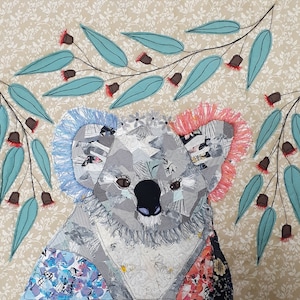 May include: A gray and white koala bear with a floral patterned fabric dress. The koala is surrounded by a blue and green leafy branch with small red flowers.