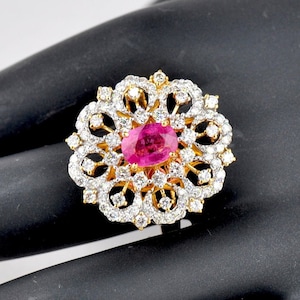 May include: A gold ring with a pink oval gemstone surrounded by smaller white gemstones in a floral design.