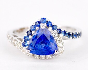 May include: A silver ring with a triangular blue sapphire surrounded by a halo of smaller blue sapphires and diamonds.