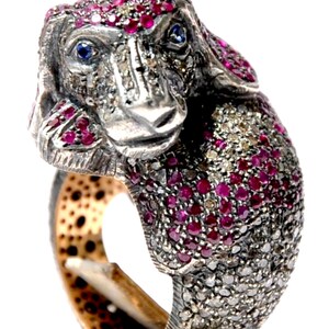 Può includere: Un anello d'argento a forma di cane con pietre preziose rosse e trasparenti. L'anello è incastonato con rubini e diamanti.