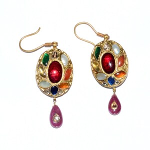 May include: A pair of gold earrings with a teardrop-shaped pendant. The earrings are decorated with a variety of colorful gemstones, including red, green, blue, and yellow.