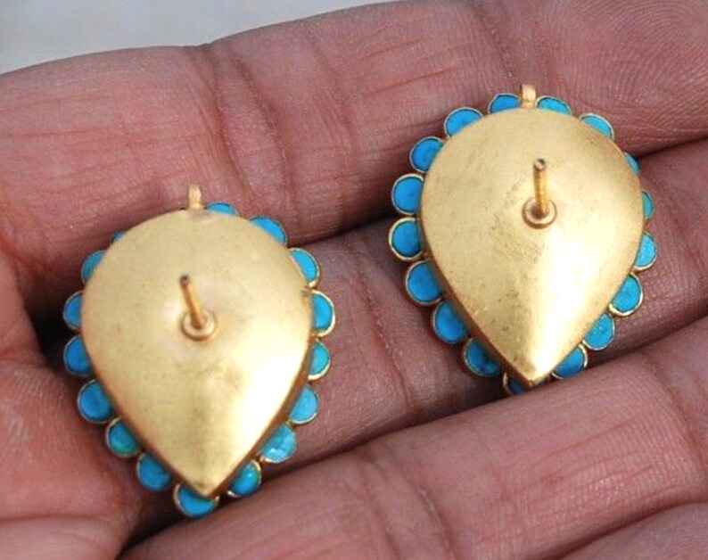 Puede incluir: Un par de pendientes de oro con piedras turquesa. Los pendientes tienen forma de l&aacute;grima y cierre de poste.