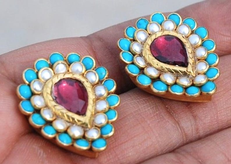 Puede incluir: Un par de pendientes de oro con una piedra roja en forma de l&aacute;grima rodeada de perlas blancas y piedras turquesa.