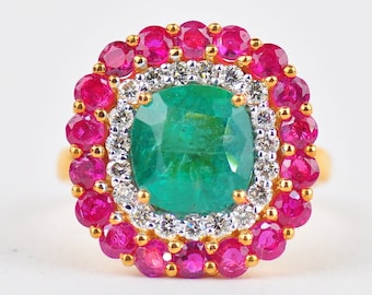 May include: A gold ring with a large emerald green gemstone surrounded by a halo of smaller diamonds and a border of ruby red stones.