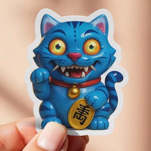 May include: A blue sticker featuring a cartoon lucky cat with a wide grin and yellow eyes. The cat has a red collar with a gold bell and holds a gold coin. The sticker is held by a hand.